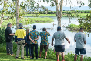 A group people look out to a wetland with their backs to the camera